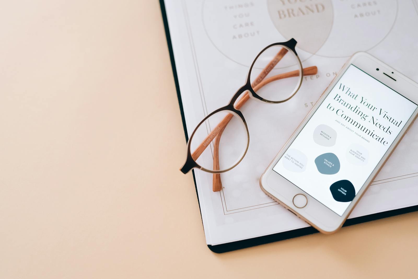 Photo by Leeloo The First Stylish flat lay of eyeglasses, smartphone, and branding document on a desk.